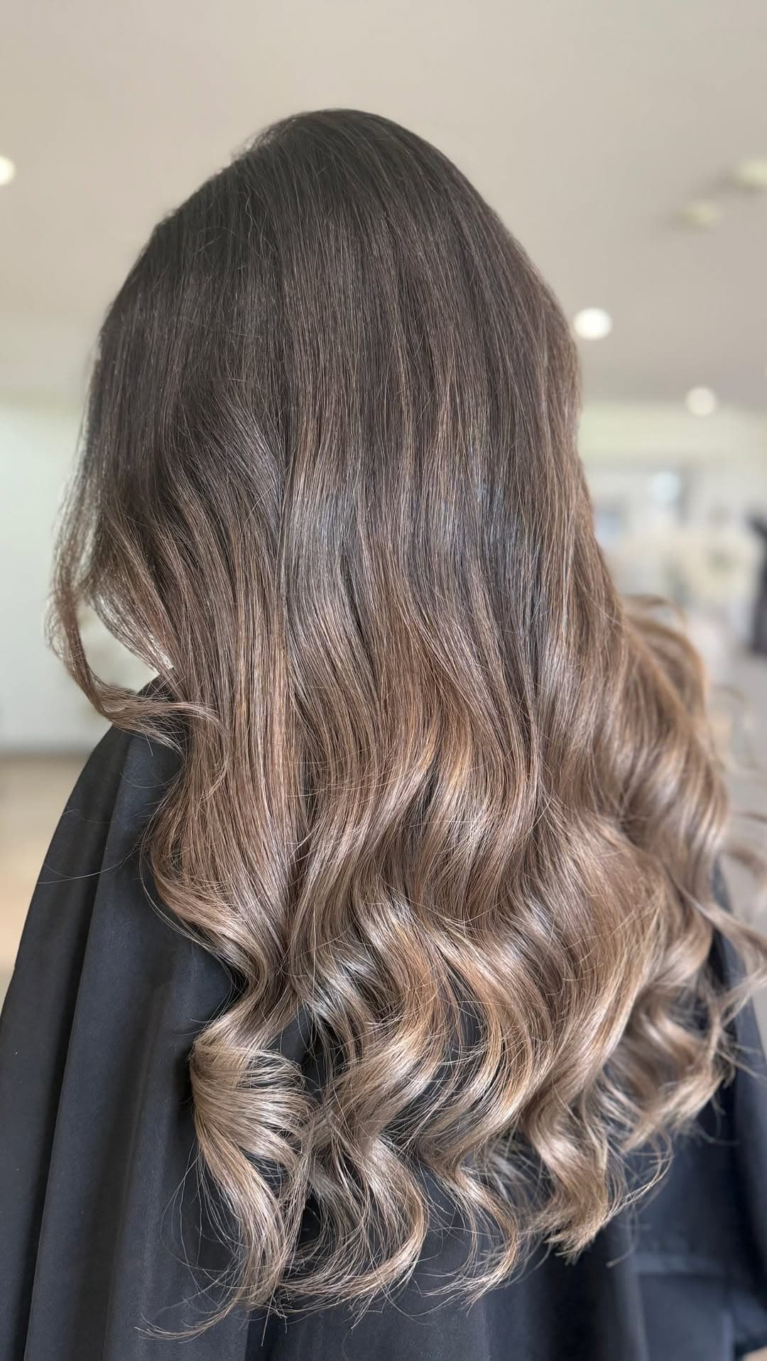 A dark root melting into bronde curled ends on the salon's black gown.