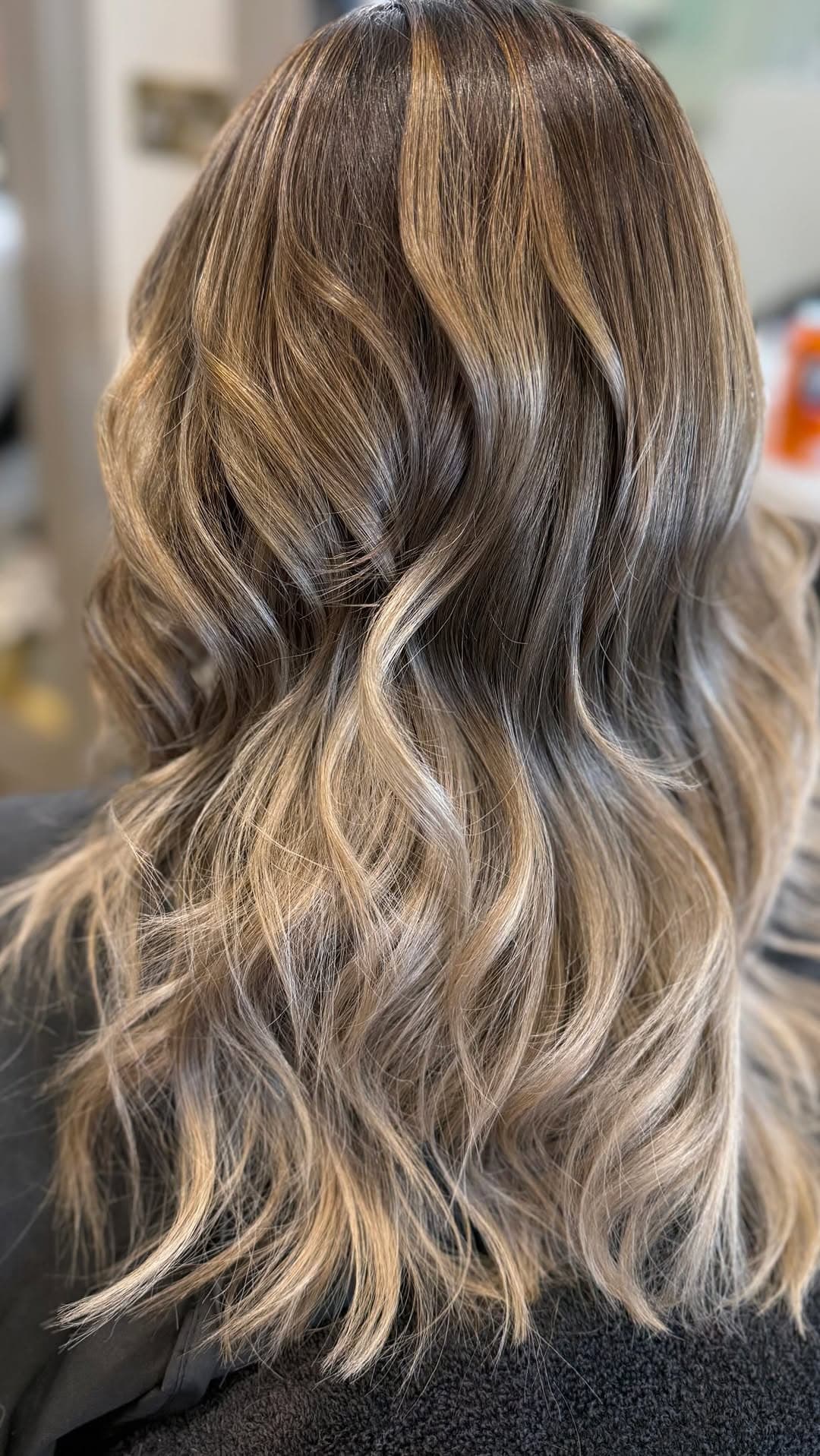 A bronde-to-blonde waved root-melt with soft golden ribbons of warmth.